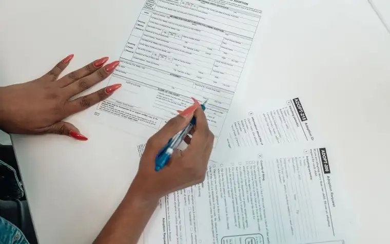 A close-up of hands filling out a dog adoption application form