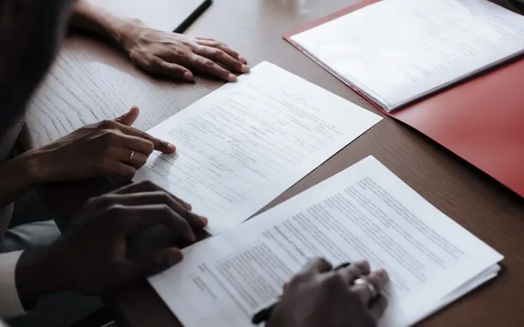 A close-up of a hand signing an adoption or purchase paperwork document