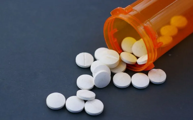 Generic prescription pills spilled from an orange pharmacy bottle