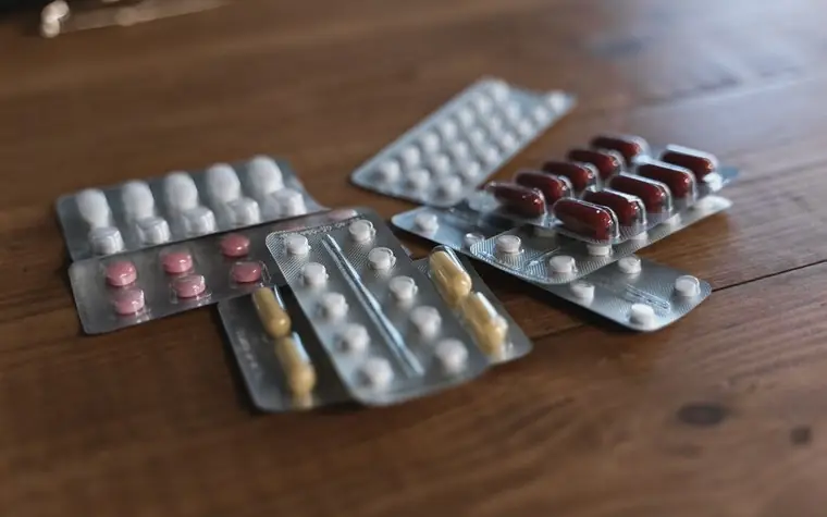 Blister packs of tablets laid out on a wooden surface