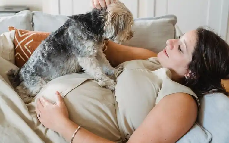 A woman relaxing on the couch with her dog