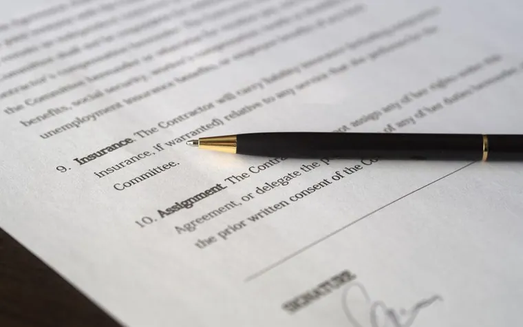 Close-up of a signed insurance contract with a black pen lying across the printed terms