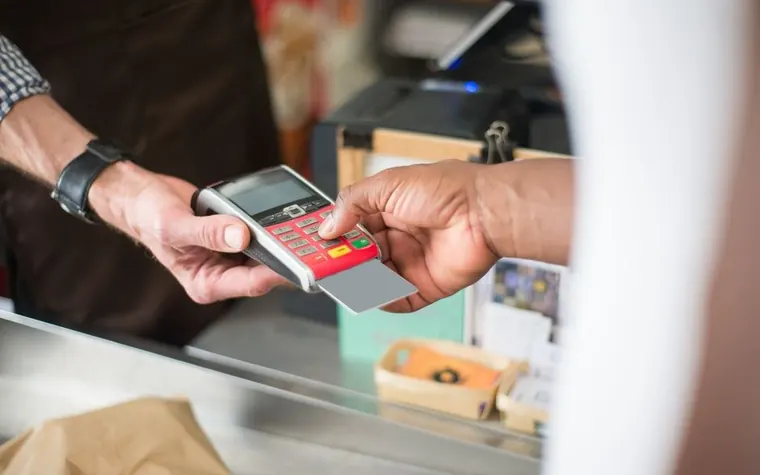 Customer holding a card to a payment terminal at a checkout counter