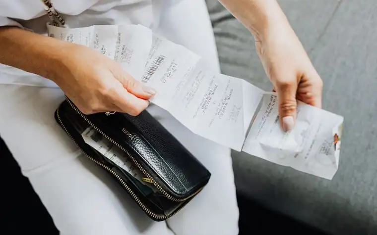 Hands sorting vet receipts above a black wallet