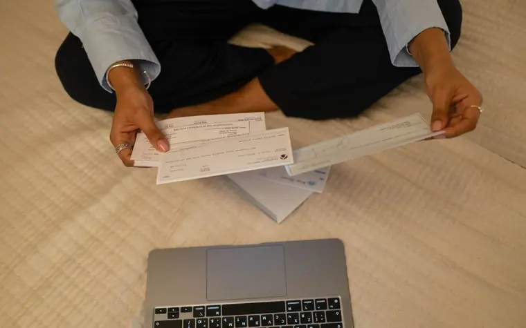 A person reviewing an insurance document beside a laptop at home