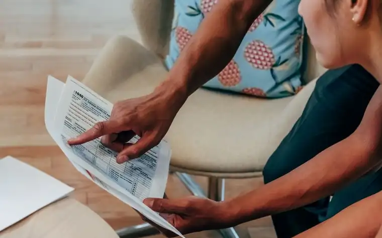 Two people reading through paperwork together at a table