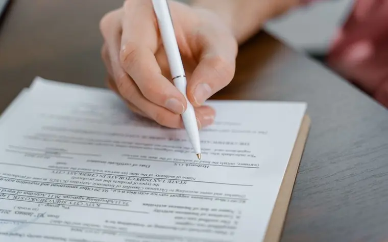 A close-up of a hand signing a document with a pen