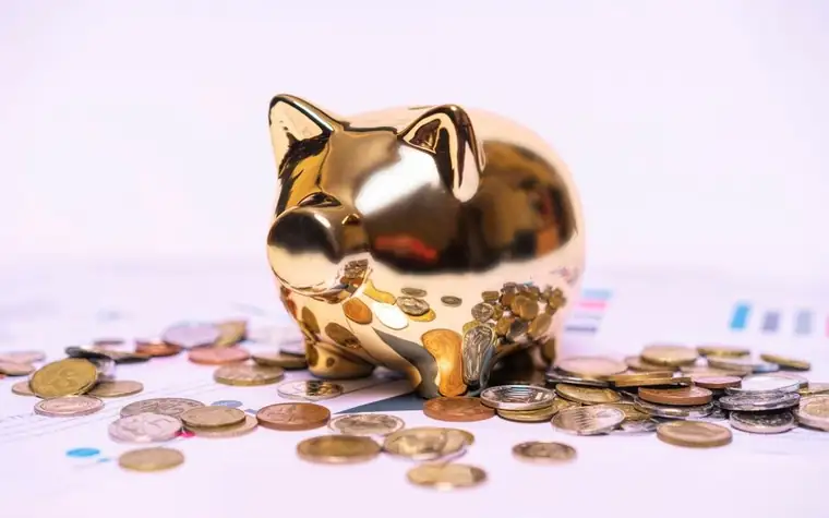 A golden piggy bank surrounded by scattered coins