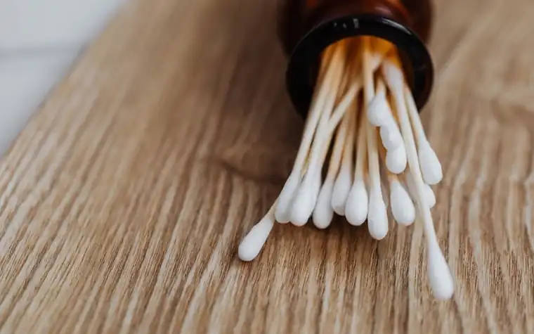 Cotton swabs standing in a glass jar on a wooden table