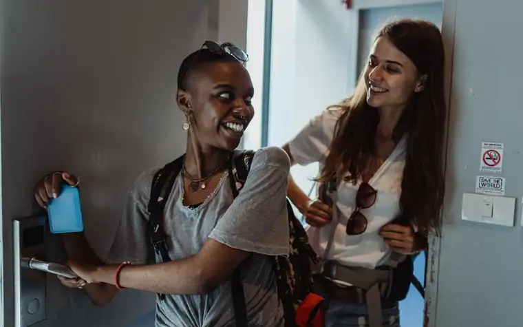 Two guests smiling while entering a hotel room with a key card