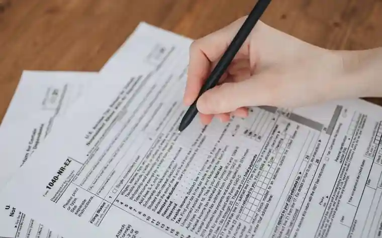 Tax forms laid out on a wooden desk with a calculator and a magnifying glass