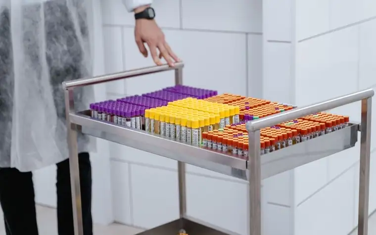 Metal cart of laboratory blood sample tubes with purple, yellow and orange caps