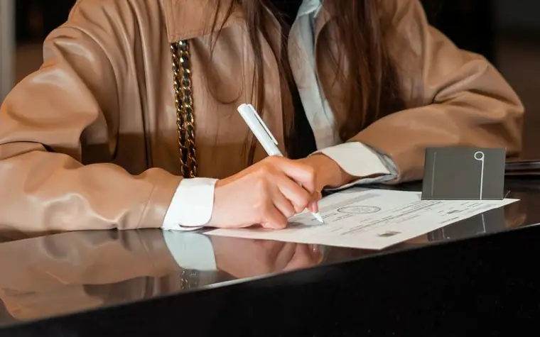 Woman signing a form at a reception counter