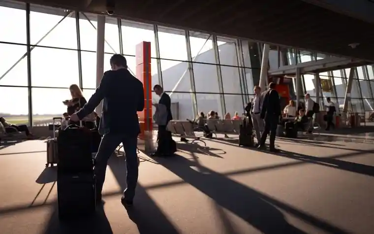 Travelers with luggage walking through an airport terminal
