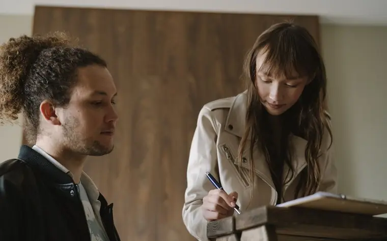 A young couple reviewing and signing rental documents at a table