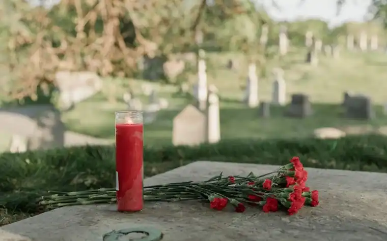 A quiet cemetery memorial scene with a candle in the distance