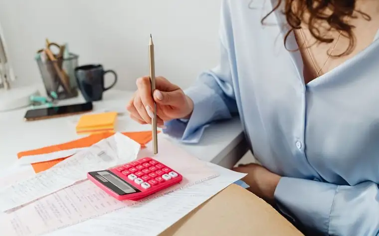 Woman using a calculator while reviewing veterinary paperwork