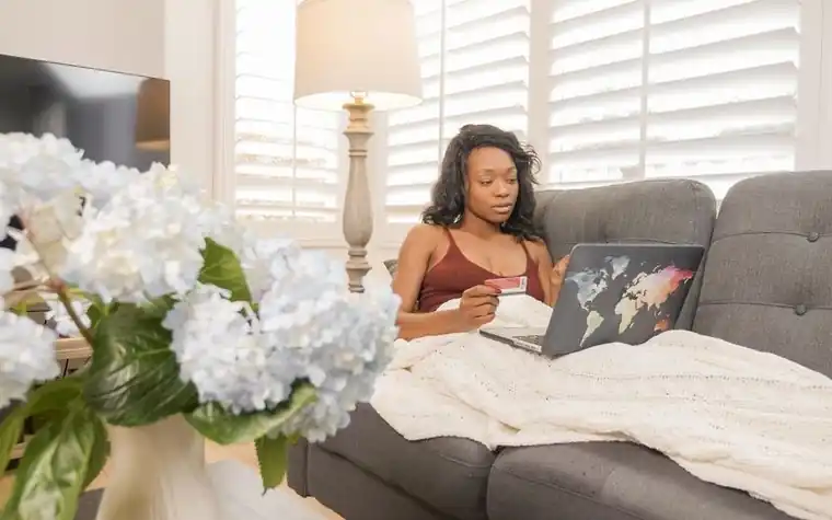 Woman on a sofa using a laptop and credit card for online shopping