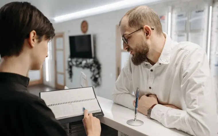 Receptionist and client talking across a clinic reception counter